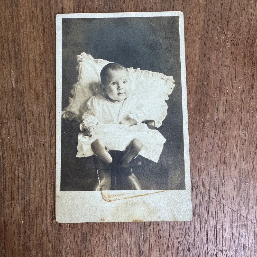 Antique Photograph on Postcard Infant Baby‎ in White Dress posing against pillow